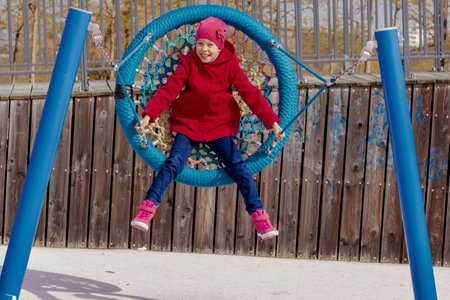 Smiling child of 8 9 years swinging on round seesaw looking at camera in motion