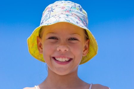 Caucasian smiling child of 8 9 years in a sun hat on clear blue sky looking at cameraの写真素材