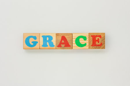 Wooden cubes with colorful painted letters spelling Grace on a flat light surface