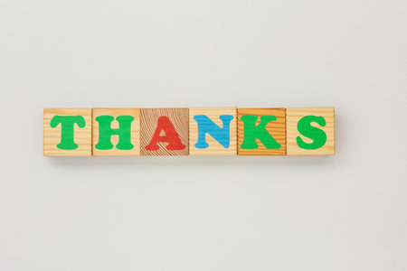 Bright wooden blocks with colorful letters to spell Thanks on a neutral surfaceの写真素材