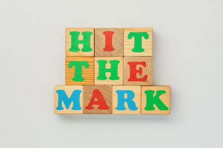 Minimalist shot of wooden blocks spelling Hit the mark on white background