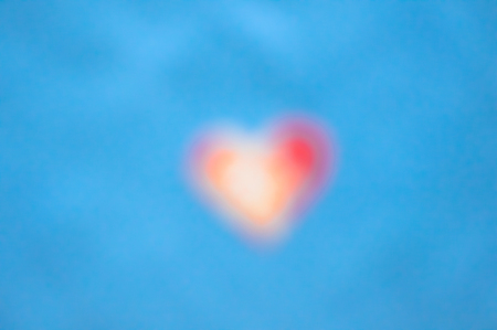 Blurred heart-shape red figure on blue backgroundの写真素材