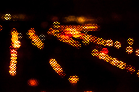 Blurred street lights through black window netの写真素材