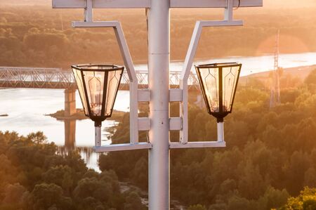 The streetlight wuth two lamps on the riverbank on sunsetの写真素材