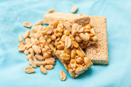 A side view at the sesame and peanut gozinaki bars on a blue tablecloth background