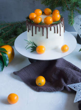 Christmas cake decorated with chocolate drips, kumquats and rosemary.の写真素材