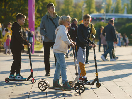 Moscow, Russia - May 10, 2022: People in the public park in the sunny spring day. street photography. Group of children with push scooters, healthy walking among a lot of peopleのeditorial素材