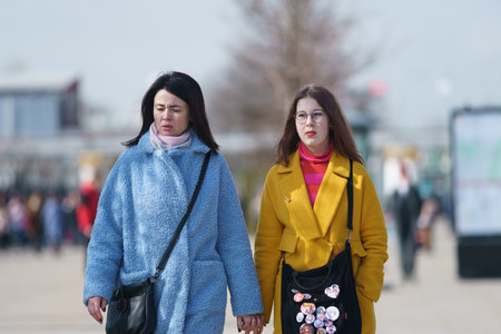 Moscow, Russia - March 28, 2023: Street photography. Mother with daughter on the city street in the spring sunny day. Portraits. Lifestyle and fashion concepts.のeditorial素材