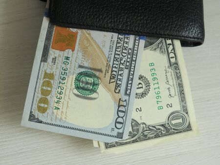 pulling focus on a folded and very used wallet with cards and cash inside on a table with a blurry...
