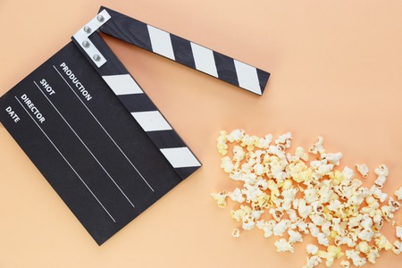 black clapperboard and popcorn with free space for text isolated on color backgroundの写真素材