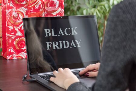 Girl sits at a laptop and makes purchases over the internet on black friday.
