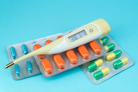 blisters with pills and thermometer lie on a blue backgroundの写真素材
