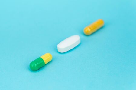 three multi-colored pills lie diagonally on a blue backgroundの写真素材