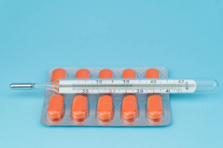 blisters with pills and thermometer lie on a blue backgroundの写真素材