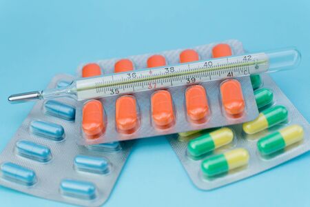 blisters with pills and thermometer lie on a blue backgroundの写真素材
