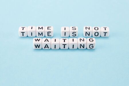 time is not waiting for you do it now - motivational phrase composed with cubes on blue backgroundの写真素材