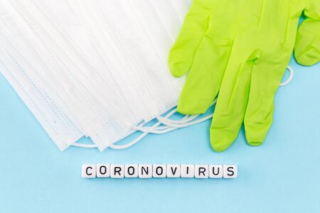 medical masks, gloves and coronovirus word composed with cubes on blue backgroundの写真素材