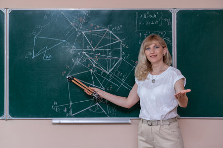 A young Caucasian female math teacher stands at the blackboard and explains the solution of a mathematical problemの写真素材
