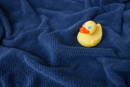 A yellow rubber duck on blue wavy towelの写真素材