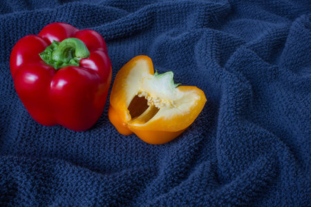 Top veiw of a red pepper and half orange pepper on a blue backgroundの写真素材