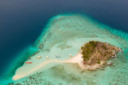 Small tropical island with a white beach. Clear sea with coral reef, top view.の写真素材