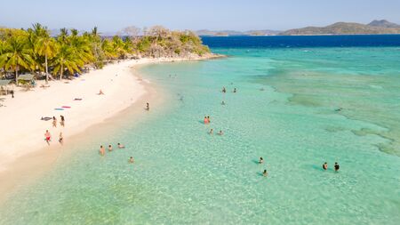 Tourists relax on the white beach. Tropical island and azure sea.の写真素材