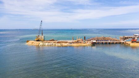 Construction of a bridge across the bay. Construction equipment on the bridge, top view. New bridge...