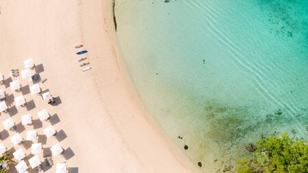 Beach umbrellas and deck chairs on the white beach. White sandy beach and clear turquoise lagoon, top view.の写真素材
