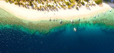 aerial view island with tropical sandy beach and palm trees. Malajon Island, Philippines, Palawan. tourist boats on coast tropical island. Summer and travel vacation concept. beach and blue clear sea waterの写真素材