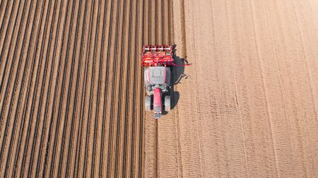 Tractor on a plowed field, top view. Agricultural field for planting vegetables. Tractor makes furrows on the field.の写真素材