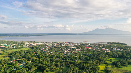 View of a small town and a volcano in the distance. Sorsogon City, Luzon, Philippines. Asian town by the sea, top view.の写真素材