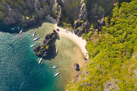 Beautiful lagoon surrounded by cliffs. Aerial drone view of swimmers inside a tiny hidden tropical...