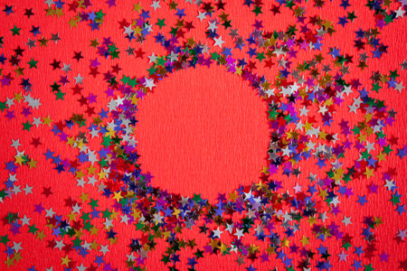 Background of multicolored confetti stars. Round frame made of stars on a red background. red shiny...