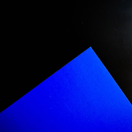 Dark flat lay background with color paper sheets. Black and blue.