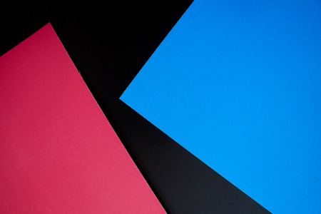 Dark flat lay background with color paper sheets. Black, blue and pink.