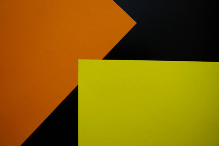 Dark flat lay background with color paper sheets. Black, orange and yellow.の写真素材