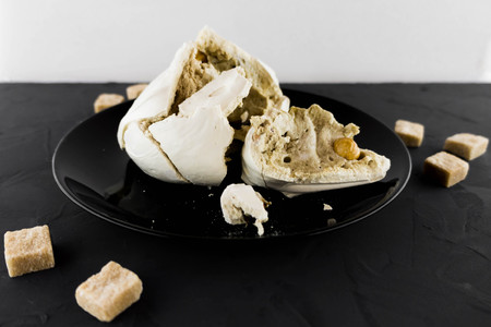 Meringue with nuts on a black plate. Macro mode. Cane sugar. Candy.
