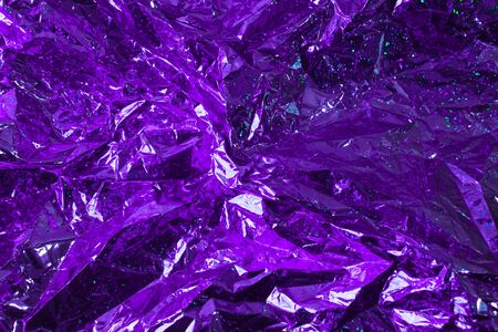 Creative photo background of violet crumpled foil with highlights and shadowsの写真素材
