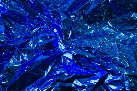 Creative photo background of blue crumpled foil with highlights and shadows