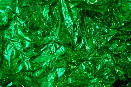Creative photo background of green crumpled foil with highlights and shadowsの写真素材