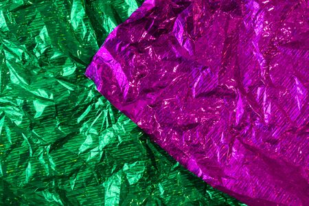 Creative photo background of green and purple crumpled foil with highlights and shadowsの写真素材