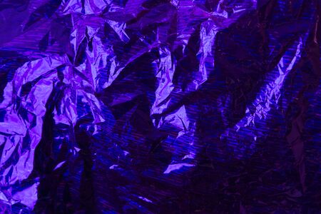 Creative photo background of blue crumpled foil with highlights and shadowsの写真素材