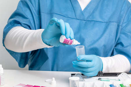a laboratory assistant in a medical suit and gloves tests water using chemical reagents