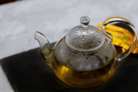 glass teapot with hot green tea on a tray on the table close-upの写真素材