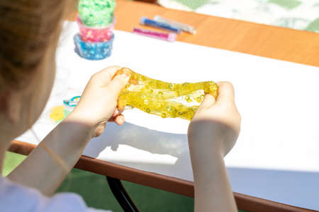 little girl playing with yellow shiny slime, back view, lifestyleの写真素材