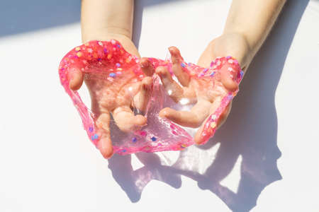 texture of decorated shiny transparent slime, baby hands with slime close upの写真素材