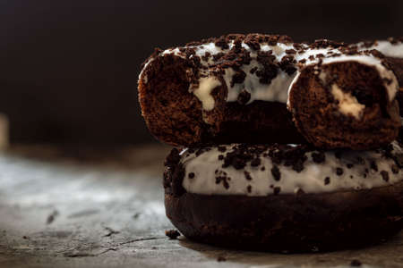 chocolate donuts with filling, covered with white icing close-up on a dark background, sweet dessert. Unhealthy food concept, food photoの写真素材