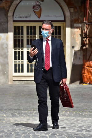 ROME, ITALY - MAY 12: Businessman in medical mask and red tie walks and speaks at phone in Piazza della Rotonda during Italian lockdown period on May 12, 2020 Rome, RM, Italyのeditorial素材