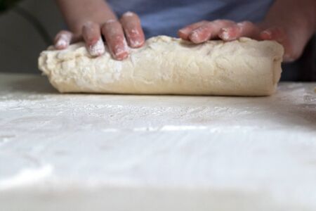 Children mold cheesecakes from dough. Kitchen table in flour. Warm relationships children.の写真素材