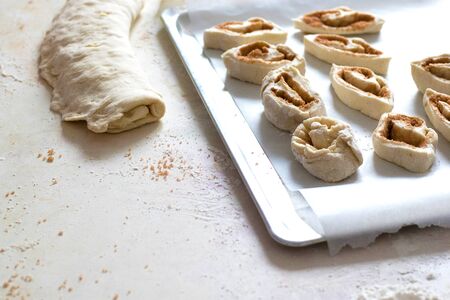 Baking lies on the tray. The process of cooking buns. On the table is flour, dough, fixtures.